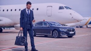 247 IAD chauffeur-stylish-man-business-suit-looking-his-phone-while-standing-front-car-near-plane-Washington-Dulles-International-Airports-Premium-Transportation-Service-Your-247-IAD-chauffeur.